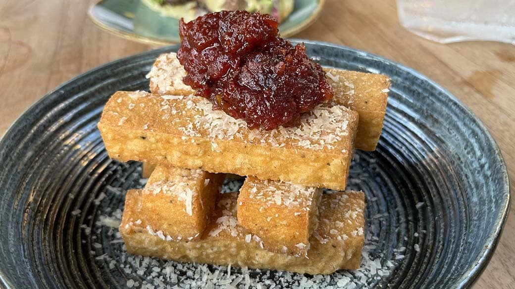 Beautifully arranged funchi hasa with Parmesan shavings and tomato jam in a kome