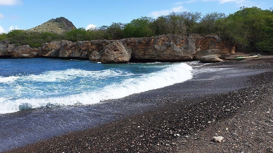 The black beach of Playa Santu Pretu on Curacao with a kayak in the background