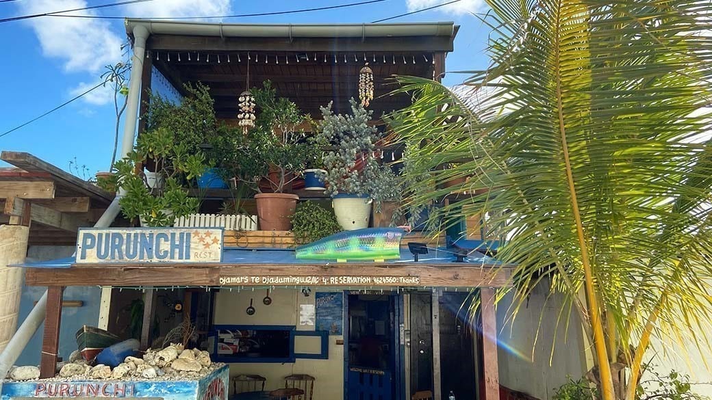Die einladende Fassade und Frontansicht des Fischrestaurants Kas di Piskadó Purunchi auf Curacao mit begrüntem Balkon und Windspielen