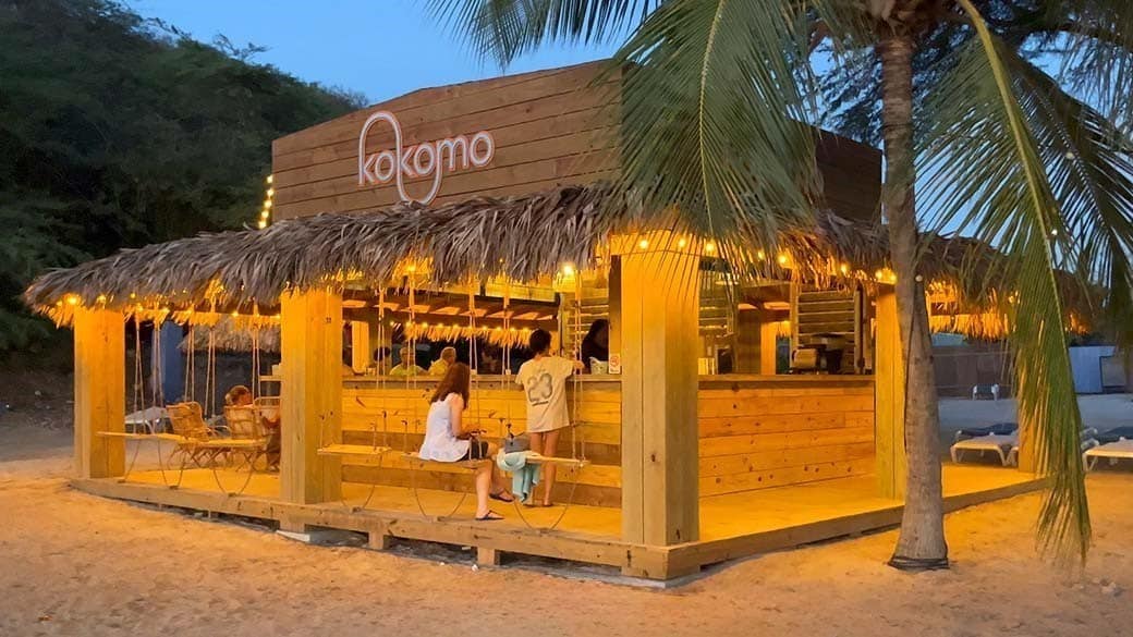Die gegen Abend beleuchtete Strandbar am Kokomo Beach mit ihren zahlreichen Holzschaukeln