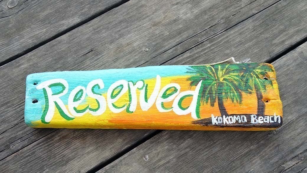 Hölzernes, handbemaltes "Reserved"-Schild auf einem Tisch der Terrasse vom Kokomo Restaurant