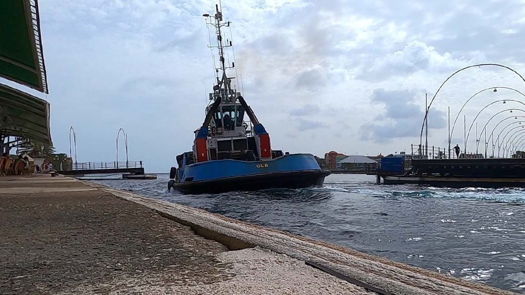Ein Schiff fährt ganz nah am Ufer des Iguana Cafés vorbei während die Brücke ein Stück weit geöffnet ist